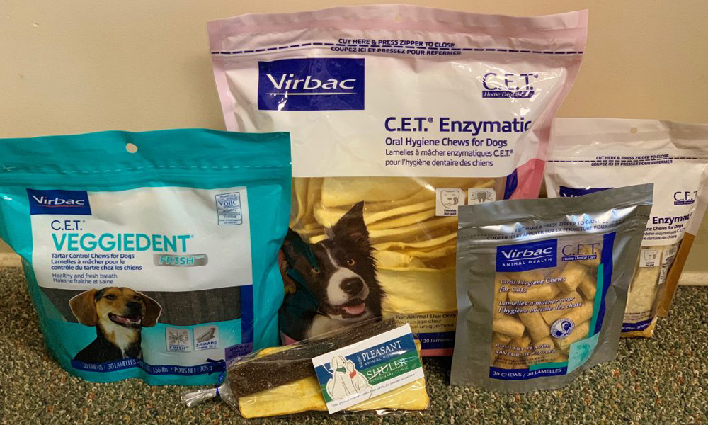 Various dog dental treat packages including c.e.t. veggiedent, c.e.t. enzymatic oral hygiene chews, and a pheasant-flavored chew recommended by veterinarians displayed on a carpeted floor.